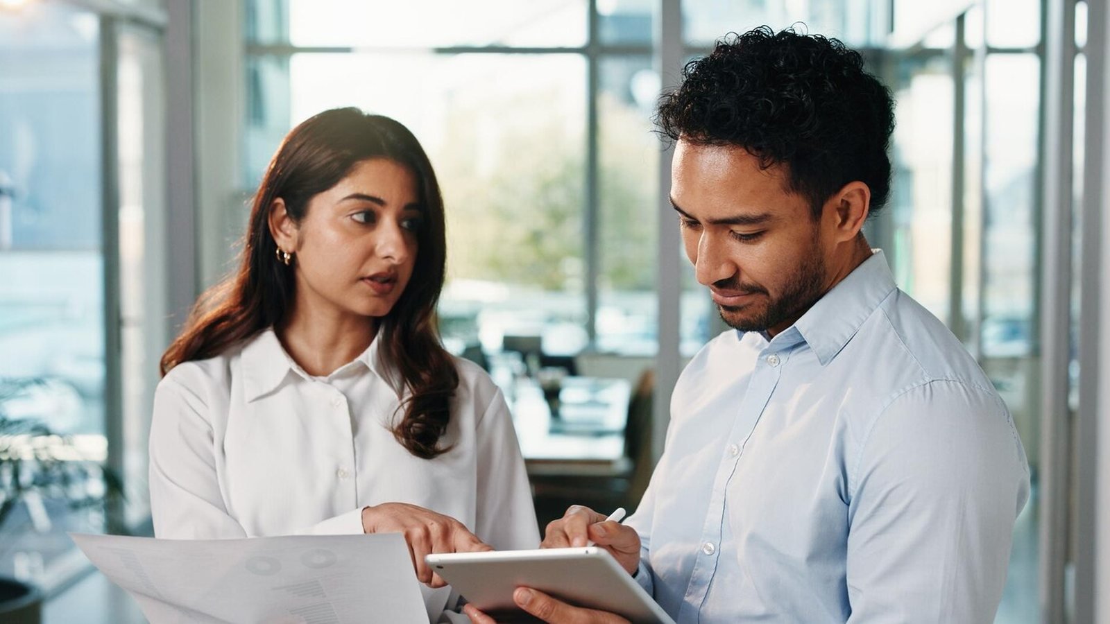 Indian procurement manager and supplier checking an accepted invoice together in a factory office